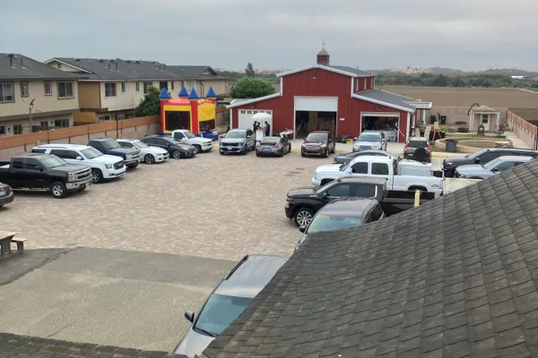Aerial view of The Red Barn during an event with parked cars and bounce house in the courtyard