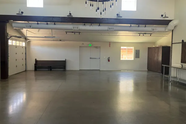 Main event hall interior — open floor, wagon wheel chandelier, and barn door accents