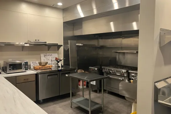Commercial kitchen with stainless-steel range, prep stations, and Red Barn signage
