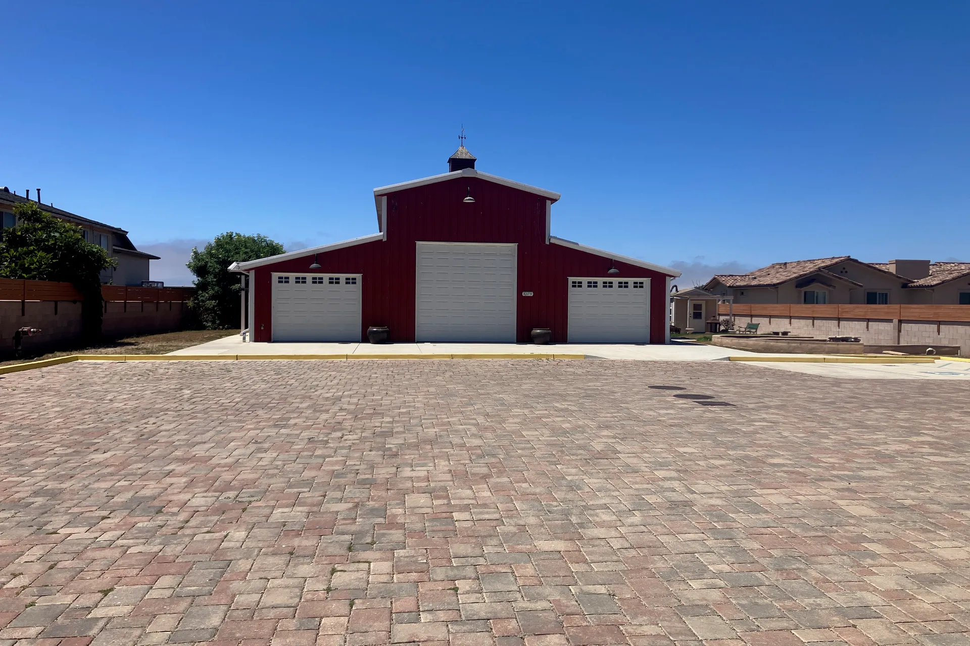 The Red Barn venue exterior — a classic red barn with large doors and paved courtyard under blue sky